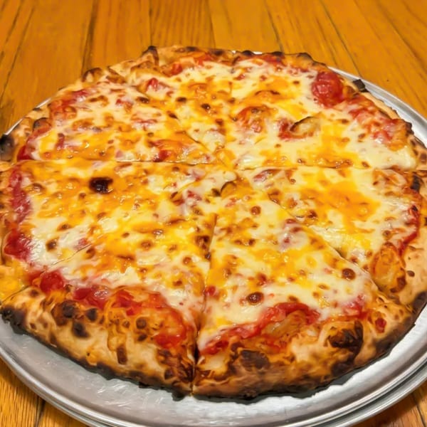 A whole cheese pizza with a golden crust, cut into slices, on a metal tray.