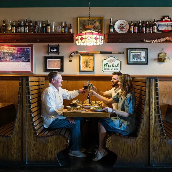 Three people toast drinks and enjoy deli food in a cozy booth at Murray's Restaurant.